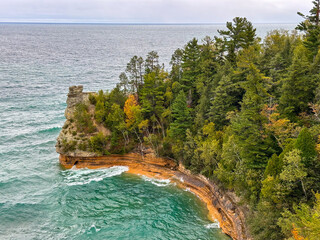 Obraz premium Miner's Castle, a dramatic rock formation in Lake Superior with trees, teal blue water, and an overcast sky
