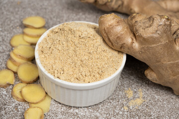 Ground ginger root powder natural spice seasoning on gray stone background