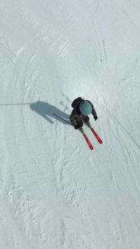 Vertical top shot from above following an amateur  skiing on a ski slope with snow in the austrian Alps