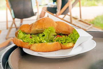 croissant with vegetables and tuna on a table in a cafe outside. Snack