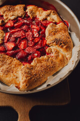 pie with strawberries on a plate, dark background, closeup