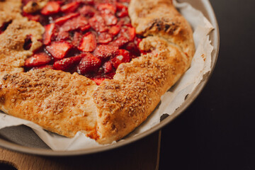 pie with strawberries on a plate, dark background, closeup