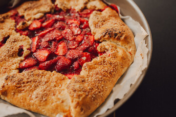 pie with strawberries on a plate, dark background, closeup