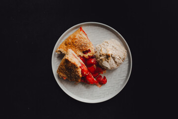 pie with strawberries and ice cream on a plate, dark background