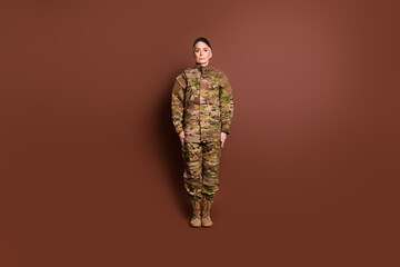 Full size photo of pretty senior female courageous servicewoman stand wear camouflage military uniform isolated on brown color background