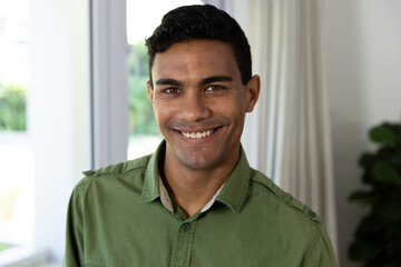 Young biracial man smiles warmly in a home setting