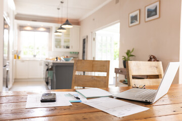 Close up of documents, smartphone and laptop lying on table over kitchen at home