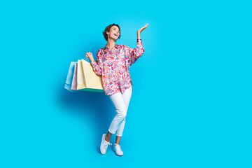 Full size portrait of pretty girl mall bags arm hold demonstrate empty space isolated on blue color...