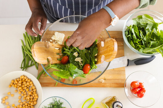 Senior african american woman making salad in kitchen at home