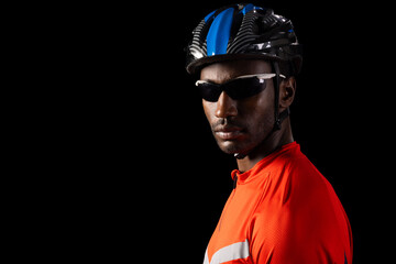 African American cyclist poses confidently on a black background, with copy space