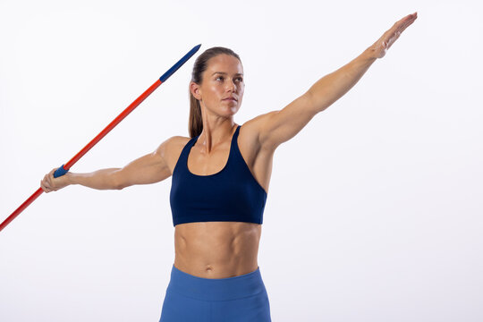 Young Caucasian female athlete prepares to throw a javelin on a white background