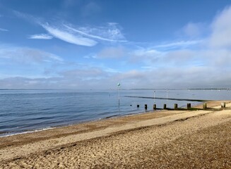 A tranquil view of calm blue waters gently lapping the beach on a bright morning in Chalkwell, Essex, England. 