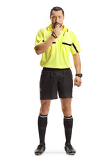 Football referee standing and blowing a whistle