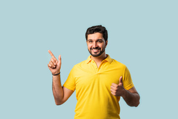 Fototapeta premium Happy Indian Asian Bearded Man Pointing at Copy Space, Looking Shocked, Blue Background
