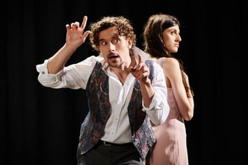 A man and woman, rehearsing for a play, stand side by side.