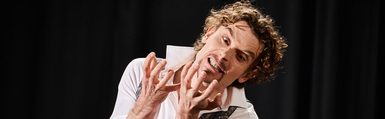 An attractive man contorts his face with his hands in a creative expression.