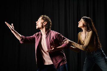 A handsome man and a woman rehearsing on a stage.