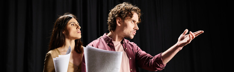 A man and woman stand poised during theater rehearsals.