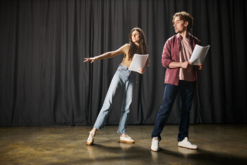 A stylish man and woman perform on a theater stage.