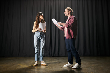 A man and a woman stand in front of an ornate curtain.