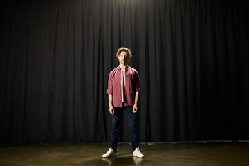 A man exudes mystery and intrigue as he stands before a striking black curtain.