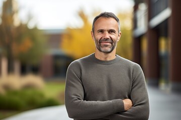 Fototapeta premium Portrait of a grinning man in his 40s wearing a classic turtleneck sweater in modern university campus background