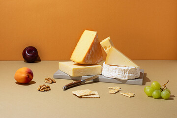 Variety of cheeses with fruits on a neutral background