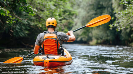 A man in a yellow helmet paddles a kayak down a river