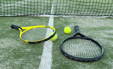 tennis racket with balls on a grass court