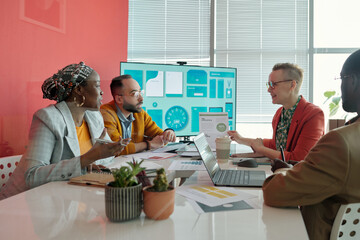 Multi-ethnic team of colleagues listening to female leader presenting business strategy during...