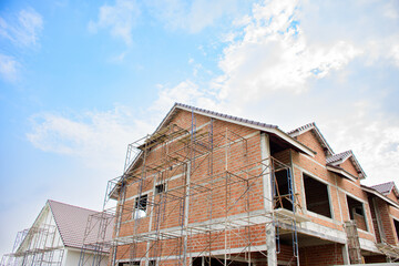 Brown building construction site with equipment for modern houses and residential new home concept 2025. Under construction and building site in progress against blue sky background.