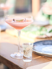 Alcoholic drink with passion fruit in a beautiful glass with a glass of vodka on a wooden table