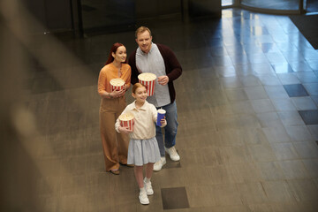 A man, woman, and a little girl stand together, embodying familial togetherness and joy in the cinema.