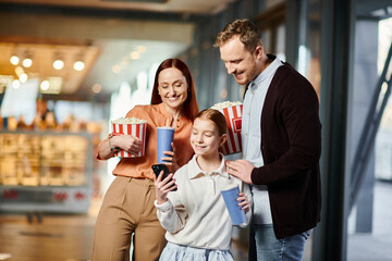 A happy family of man, woman, and child gathered together, engaged in looking at a cell phone screen.