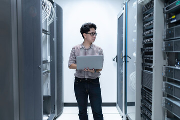 Computer engineer is setting up network in server room,Systems Maintenance Technician,Male engineer working in server room at modern data center