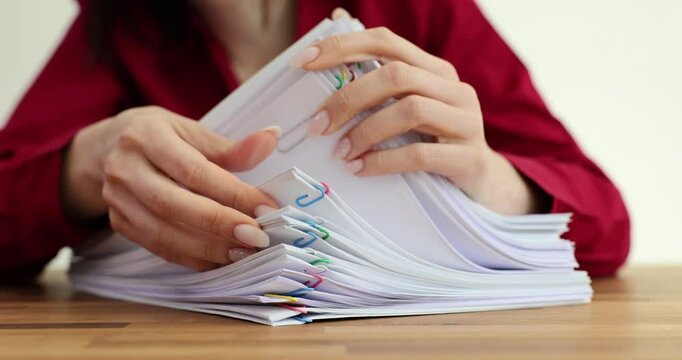 Female worker inspects stack of papers fastened with clips