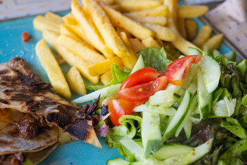 Plate of French Fries with Fresh Salad. Close-up of crispy French fries served with fresh salad on...