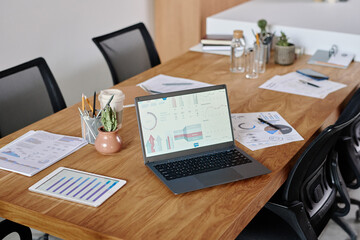 High angle shot of workplace equipped with digital devices and brochures with analytical diagrams and decor items