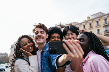 Smiling diverse friends taking a selfie in the city with an urban background.