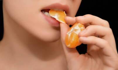 Woman Eating an Orange Slice. Close-up of a woman about to eat a slice of orange against a black...