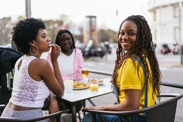 Group of African women enjoying food and drinks at an outdoor tavern.
