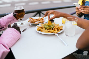 Close-up of nachos and beer at an outdoor city tavern table.