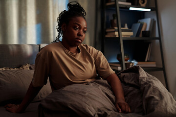 Young African American woman in trouble staying up all night unable to get asleep while remembering...