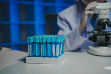 Scientist conducting important research in a modern laboratory using a microscope and test tubes...