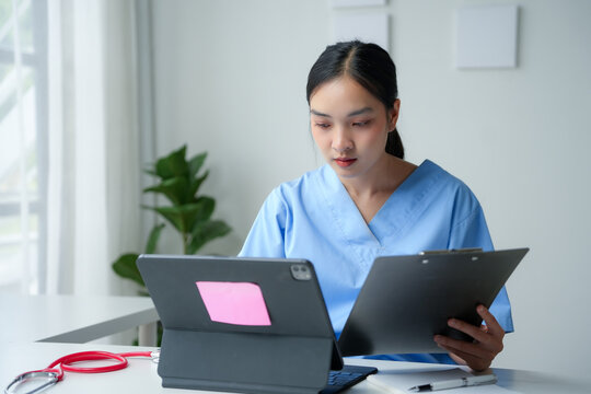 Attentive asian woman physician uses modern healthcare technology to review medical records on a tablet and clipboard