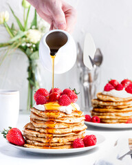 Stack of pancakes with syrup, cream and berries