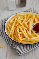 Homemade American French Fries with Ketchup on a Plate, side view.