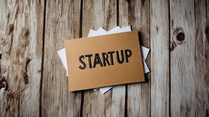 Wooden background with brown paper with the word startup written, business and innovation concept.