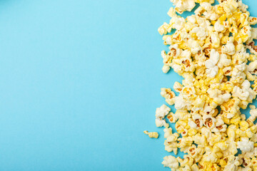 Salted popcorn on a blue background. Cinema and entertainment concept. Movie night with popcorn. Delicious appetizer, snack. Place for text. Copy space. Banner