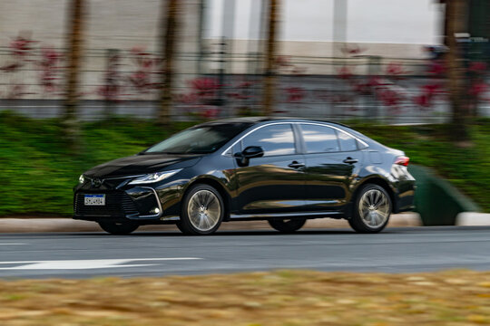Black Toyota Corolla cruising in city street, Luxury sedan in movement, High resolution Panning Shot